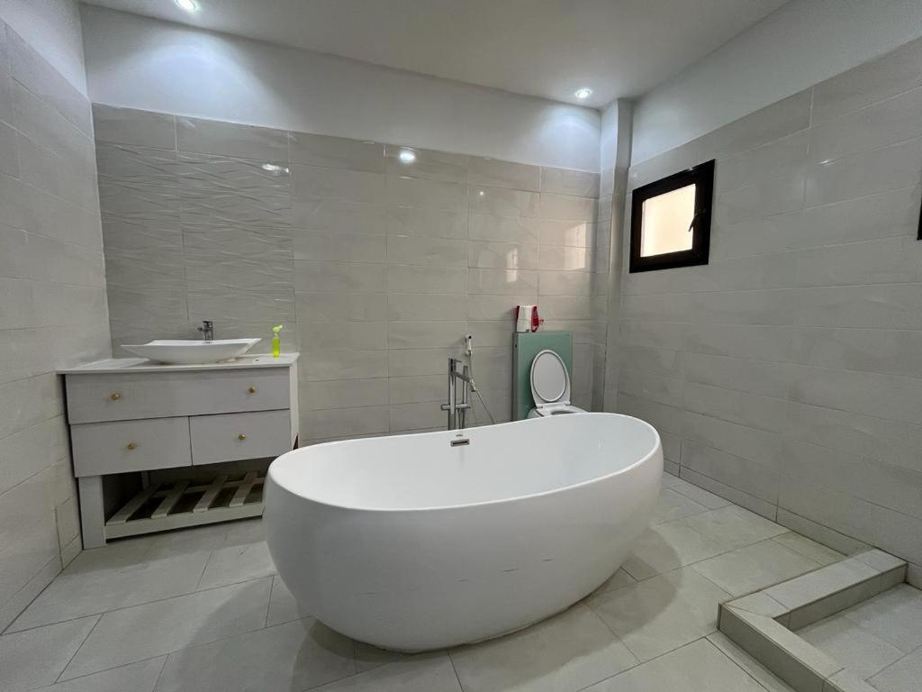 a white bathroom with a tub and a sink at Keeluxe Cite Keur Gorgui- Superbe appartement in Dakar