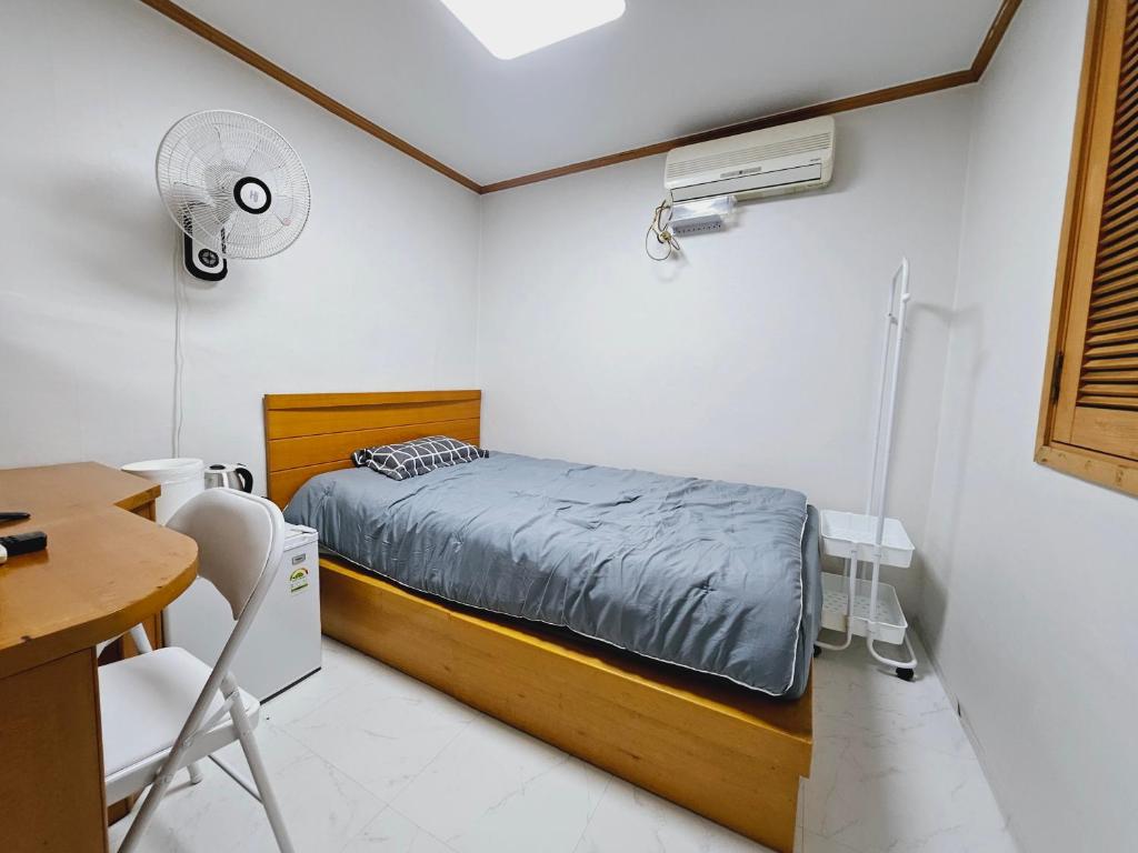 Schlafzimmer mit einem Bett und einem Schreibtisch mit einem Ventilator in der Unterkunft K Highstel in Seoul