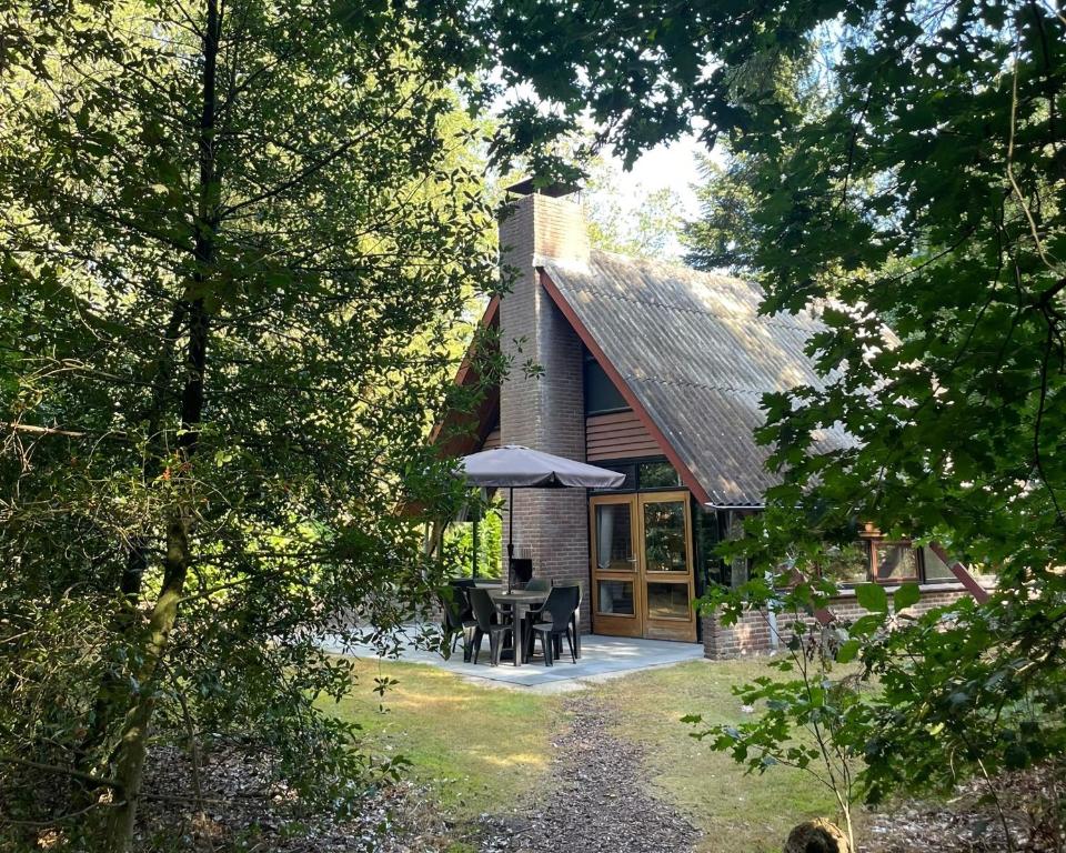 una casa con mesa, sillas y sombrilla en Summio Vakantiepark Herperduin, en Herpen
