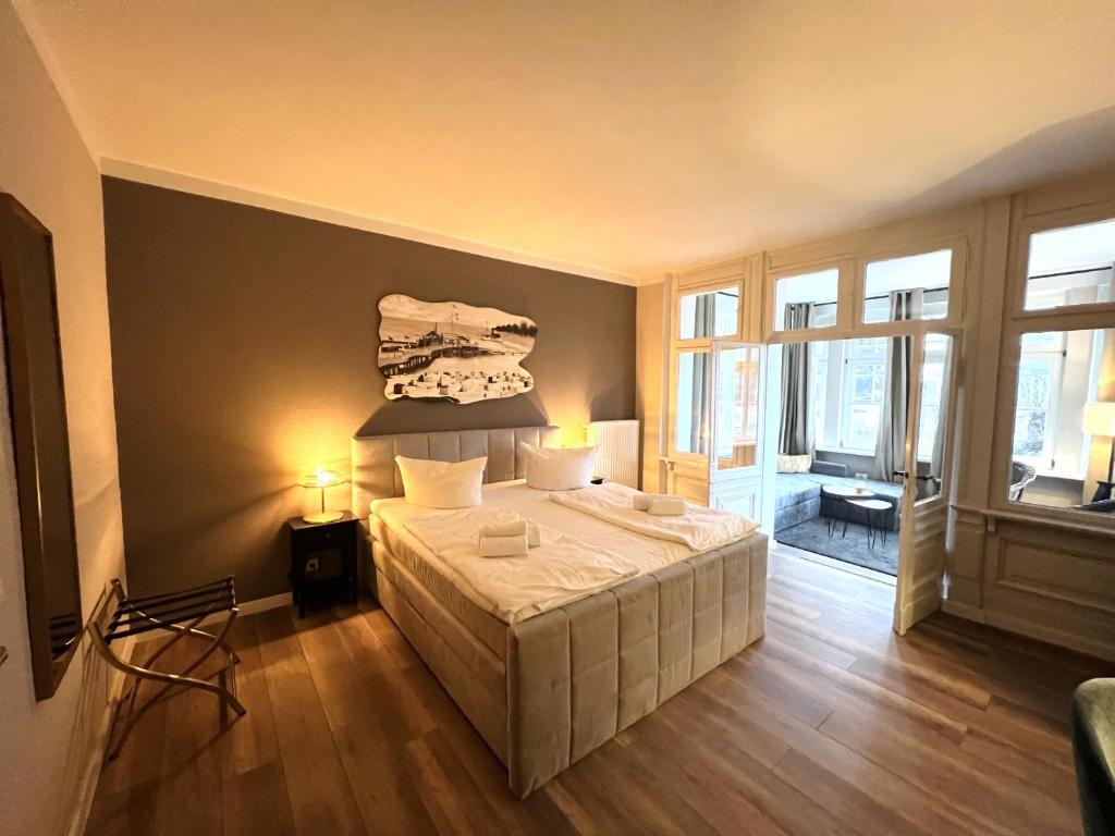 ein Schlafzimmer mit einem großen Bett in einem Zimmer mit Fenstern in der Unterkunft Hotel Garni BALTICpetite in Heringsdorf