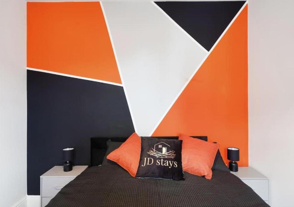 a bedroom with an orange and black wall at 4 Bedroom Apartment, near the airport & Free WiFi-Parking in Lincolnshire