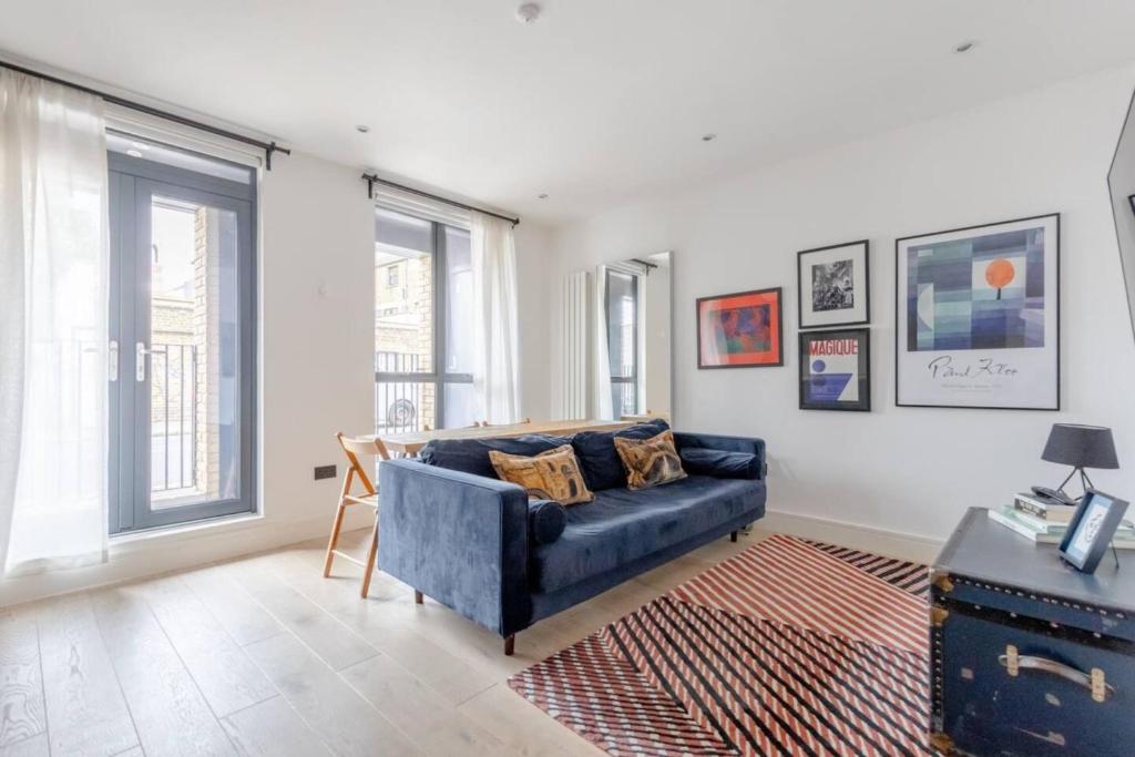 a living room with a blue couch and some windows at Charming & Stylish 1BD Flat - Bethnal Green in London