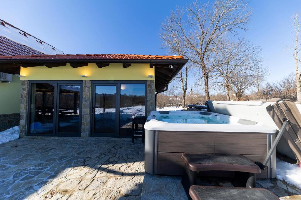 uma banheira de hidromassagem sentada fora de uma casa em SPA HOLIDAY HOUSE REŽEK - Lovinac em Lovinac