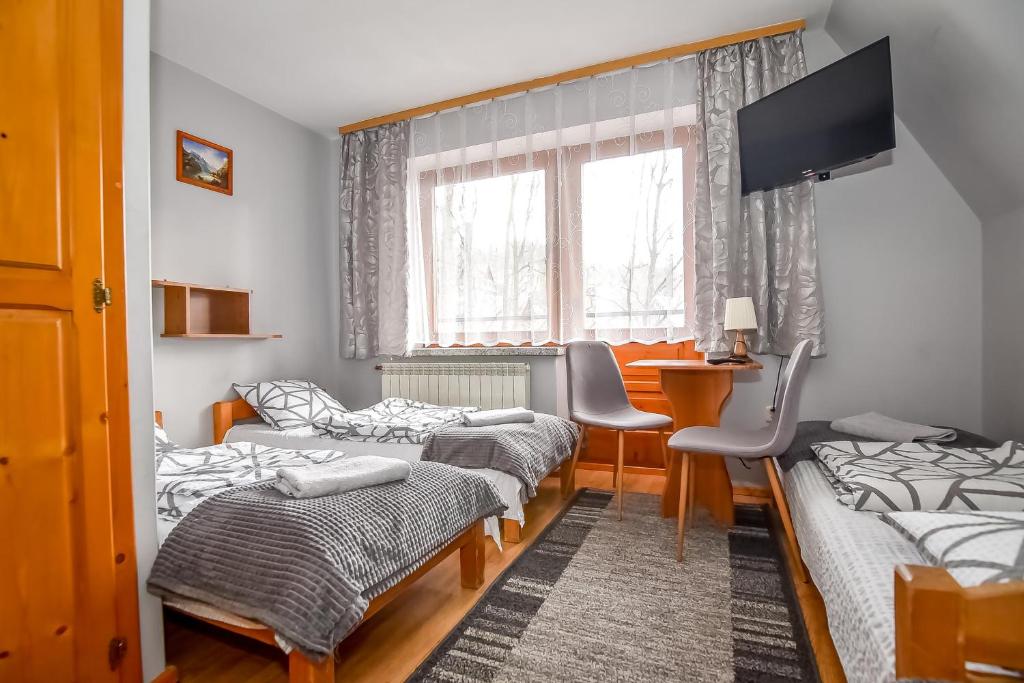 a room with three beds and a table and a window at U Cudzicha in Zakopane