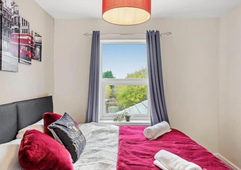 a bedroom with a bed with a pink blanket and a window at 3 Bedroom House with Non-smoking, great location, free Wi-Fi & Parking in North Hykeham