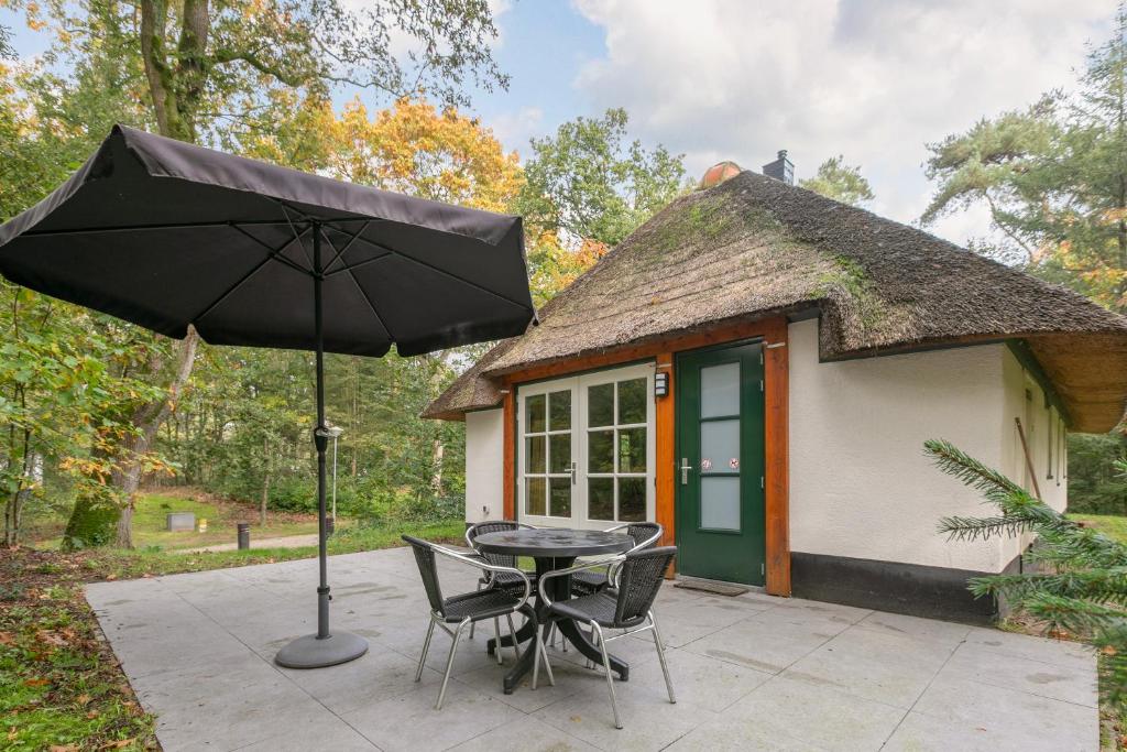 a patio with a table and chairs and an umbrella at Summio Vakantiepark Herperduin in Herpen
