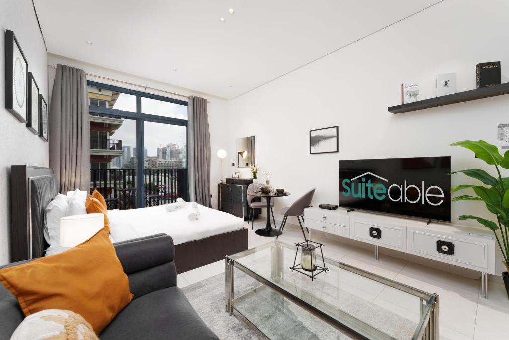 ein Wohnzimmer mit einem Sofa und einem TV in der Unterkunft Cozy Studio in Beverly Residence, JVC by Suiteable in Dubai