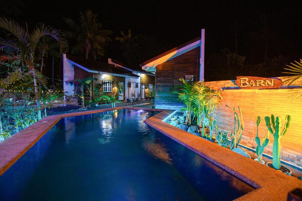 a swimming pool in front of a house at night at Barn Hostel in Panglao