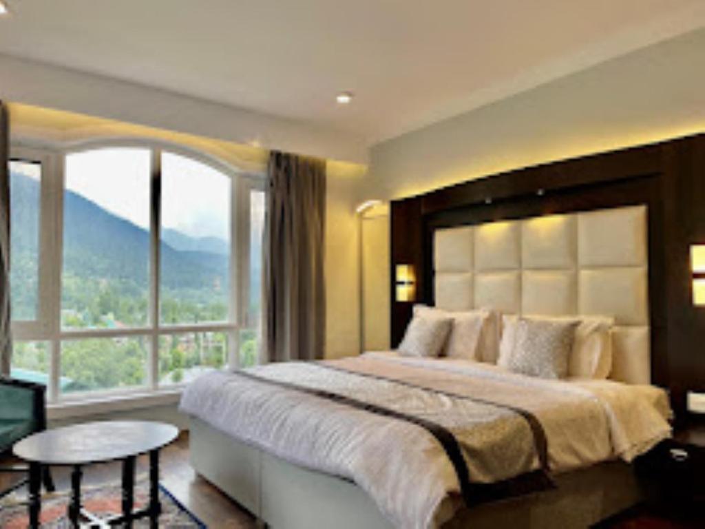 a bedroom with a large bed with a large window at Forest Hill Resorts Laripora in Pahalgām
