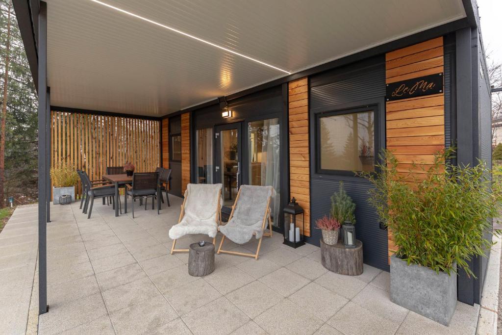 a patio with two white chairs and a table at Apartma LeMa in Velike Lašče