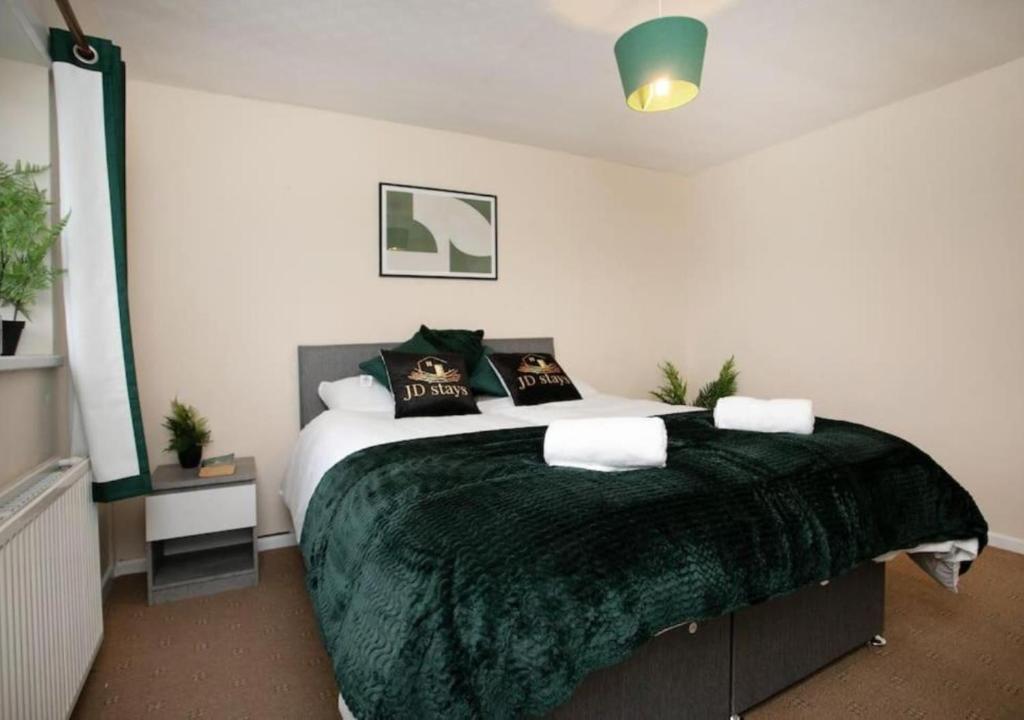 a bedroom with a large bed with a green blanket at 3 Bedroom Apartment - Huge cut price on long stays in Lincolnshire