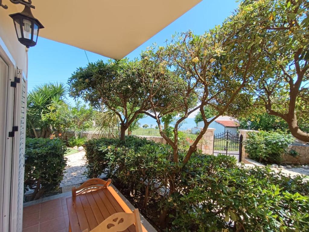 a porch with a wooden bench and trees at Calypso Studios in Amoudi