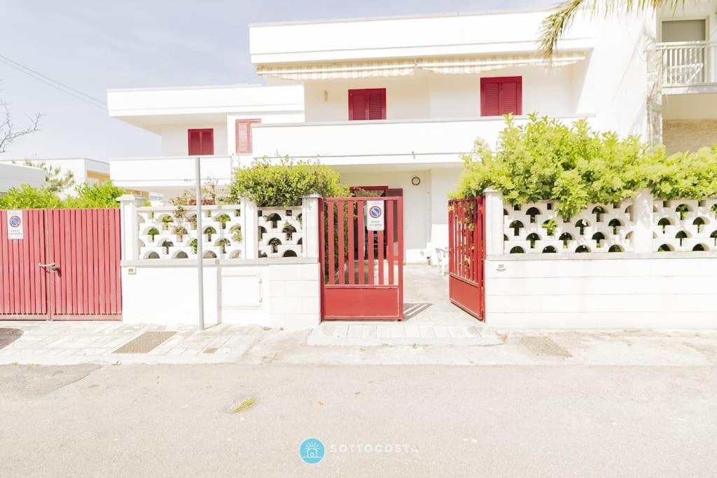 a red gate in front of a white house at Orsetta Flat - Torre Dell'Orso in Torre dell'Orso
