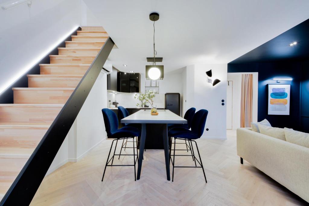 a dining room with a table and chairs and a staircase at Le Splendide de Poincaré in Nancy