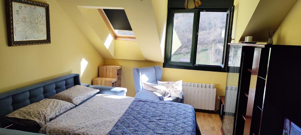 Un dormitorio con una cama y una silla y ventanas. en Apartamento rural Felechosa, en Felechosa