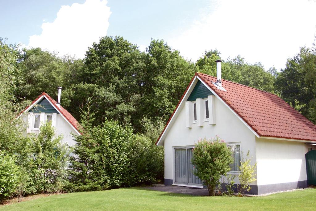 una pequeña casa blanca con techo rojo en Summio Bungalowpark Het Drentse Wold, en Hoogersmilde
