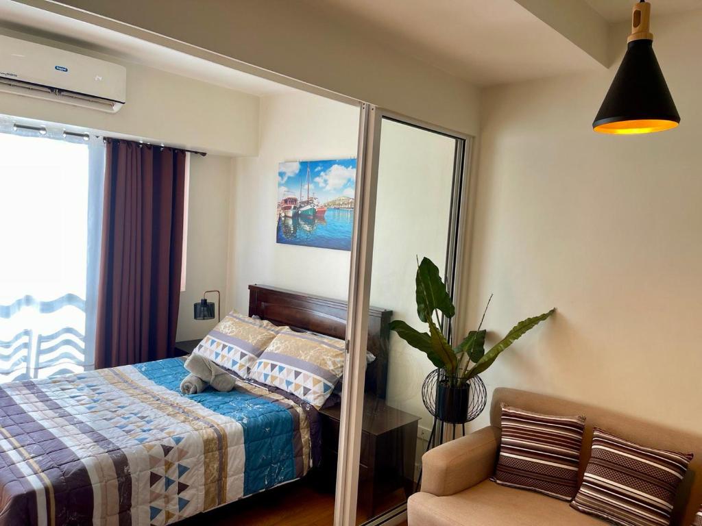 a bedroom with a bed with a mirror and a chair at Great 1BR Aqua Livingstone with Netflix, Pool & Gym in Manila