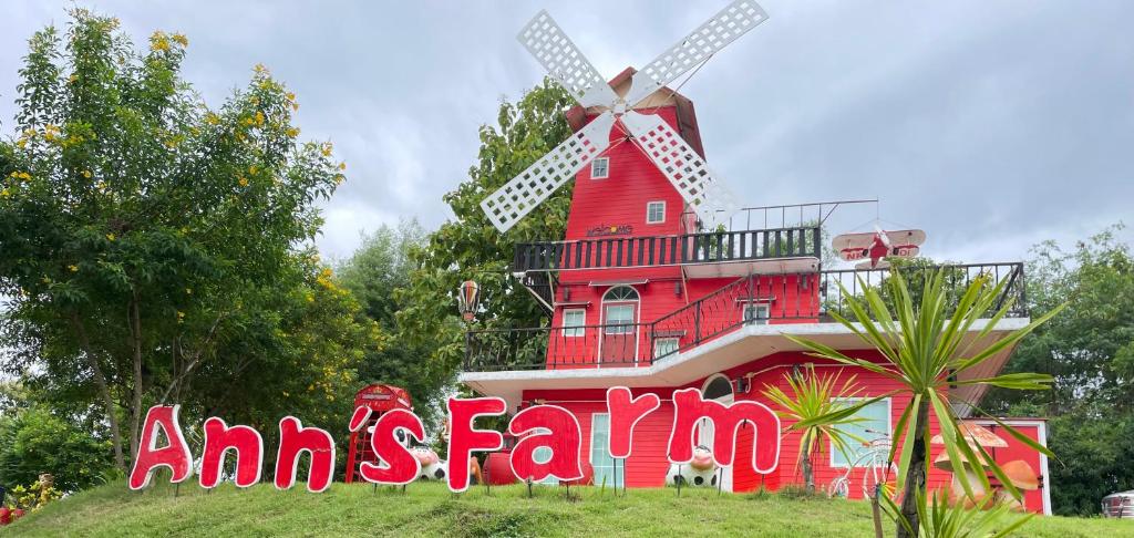 ein rotes Haus mit einer Windmühle davor in der Unterkunft แอนฟาร์มรีสอร์ทแอนด์คาเฟ่ลำปาง 