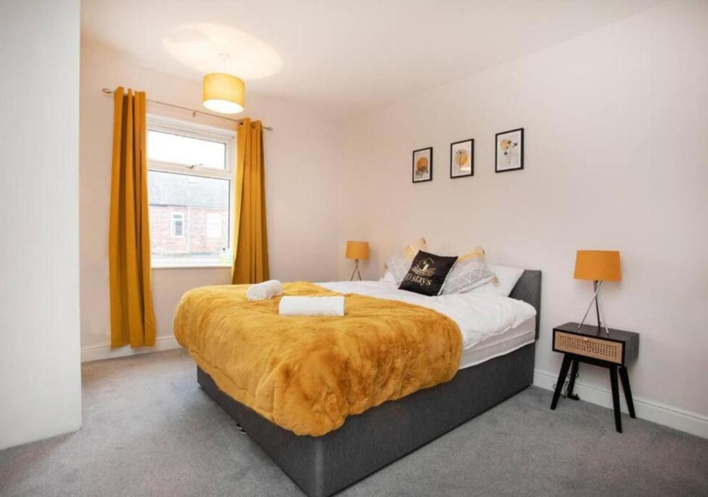 Un dormitorio con una cama grande con una manta amarilla. en 4 Bedroom Apartment with non-smoking room, easy access to all amenities, free Wi-Fi & Parking - Big monthly price reduction, en Lincolnshire