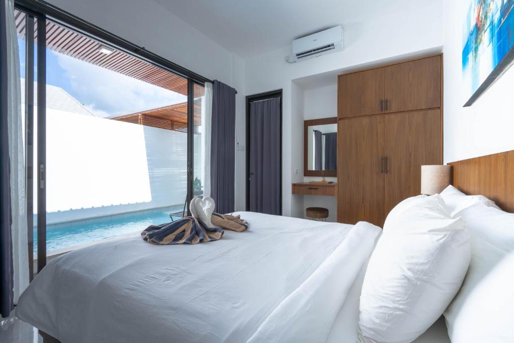 a bedroom with a large white bed with a large window at The Lavana De Mello's Villa Seminyak -1 Bedroom Villa with Private Pool in Kerobokan