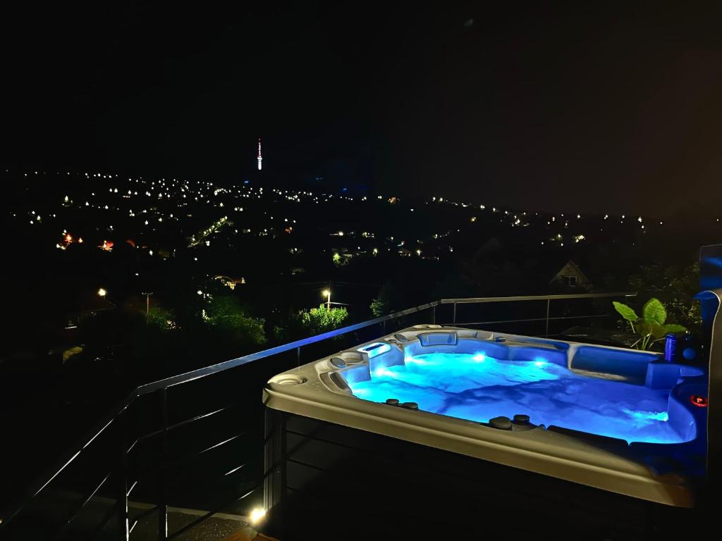 a jacuzzi tub on a balcony at night at Mythos Private Resort in Pécs