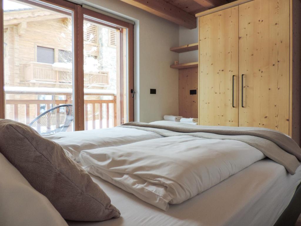 - une rangée de lits blancs dans une chambre avec fenêtre dans l'établissement Nix apartment, à Livigno