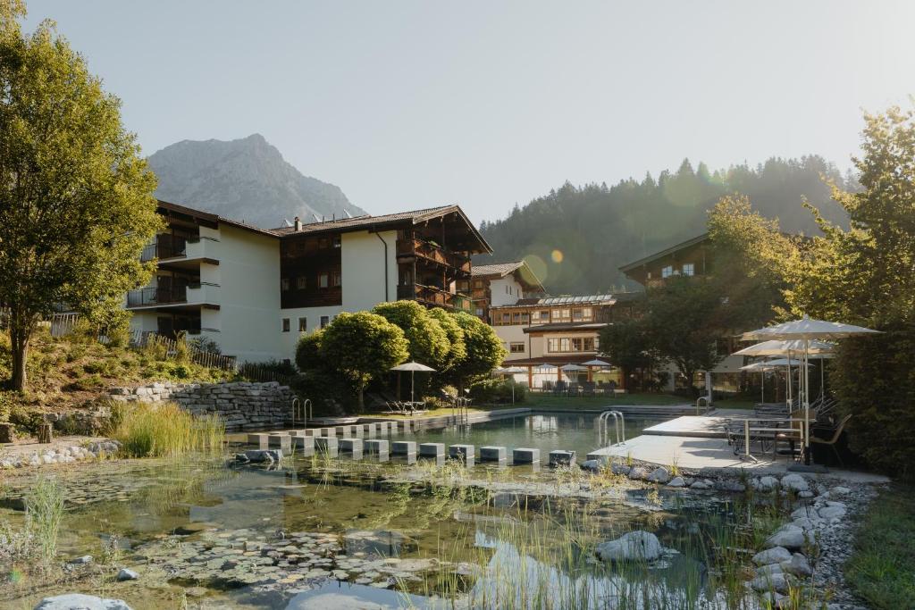 a resort with a pond in front of a building at Hotel Kaiser in Tirol in Scheffau am Wilden Kaiser