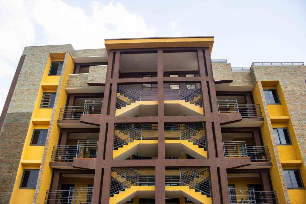 un edificio alto de color amarillo con balcones. en Fully Furnished 1- Bedroom in East Legon en Madina