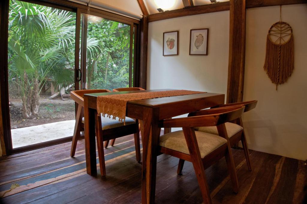 a wooden table and chairs in a room with a window at Cabaña Chechen, wooden chalet in tropical garden in Isla Mujeres
