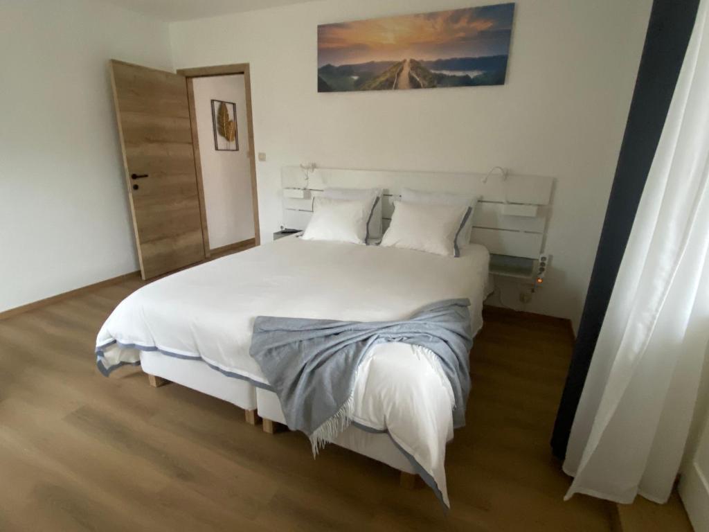 a bedroom with a large bed with white sheets and pillows at D-012 Bel appart et balcon climatisé parking privé gratuit sur demande in Charleroi