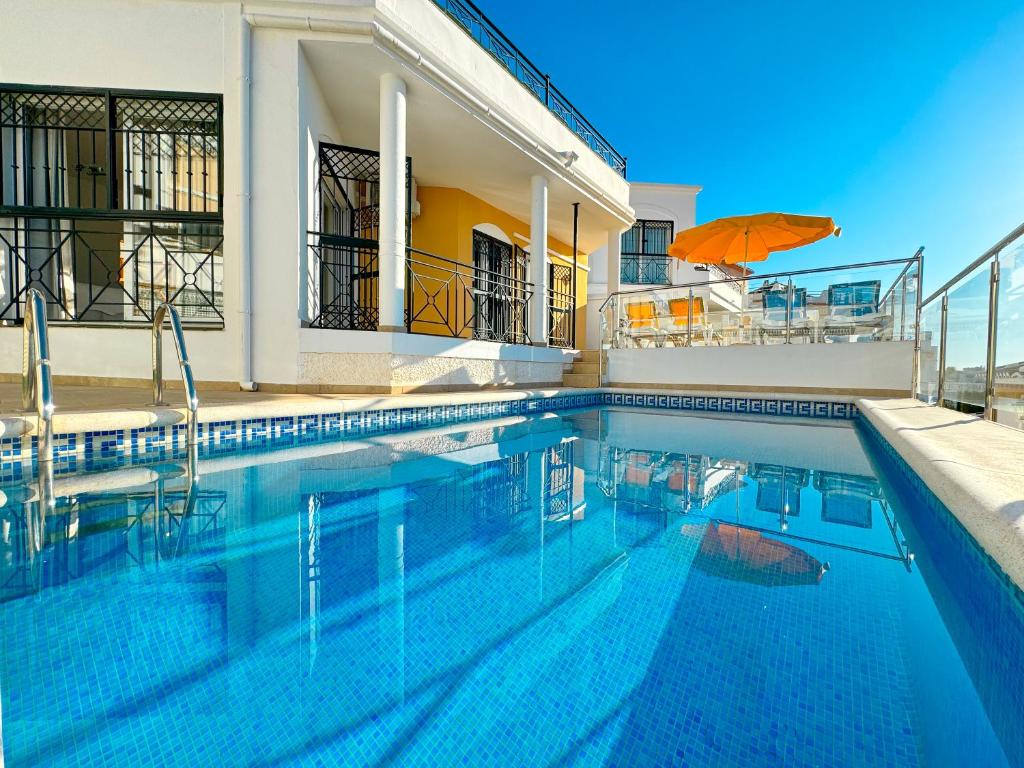 ネルハにあるVilla Jazminの傘付きの家の前のスイミングプール