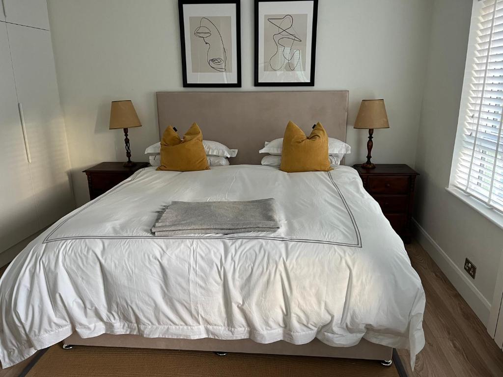 Una cama blanca con dos almohadas amarillas. en Central town location apartment, en Enniscorthy