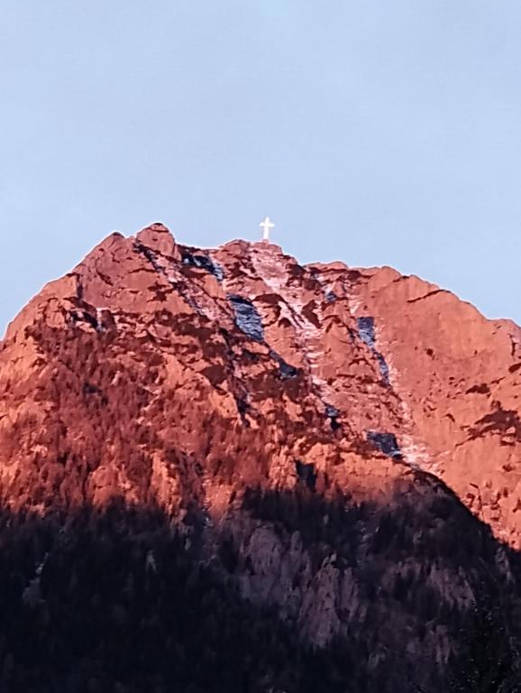 uma montanha com uma cruz em cima dela em Casa cu Flori em Buşteni