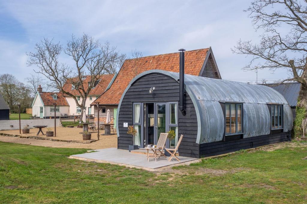 a black tiny house with a tin roof at The Nissen Hut at Green Valley Farm in Laxfield