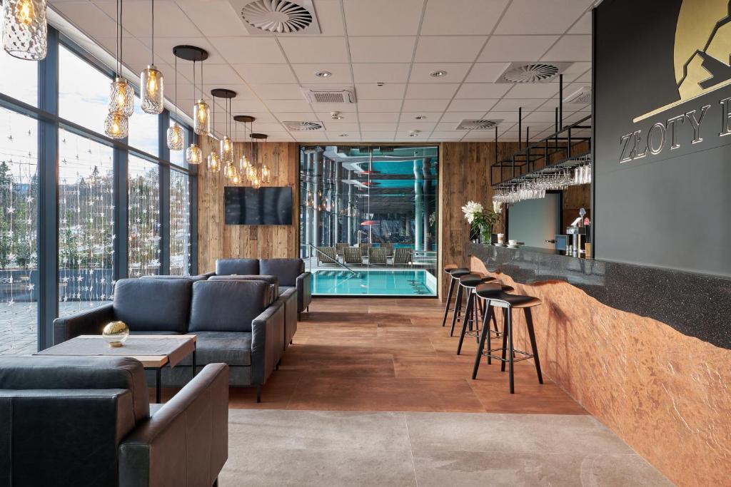 Contemporary hotel lounge and bar with leather seating, pendant lights, and indoor pool view.
