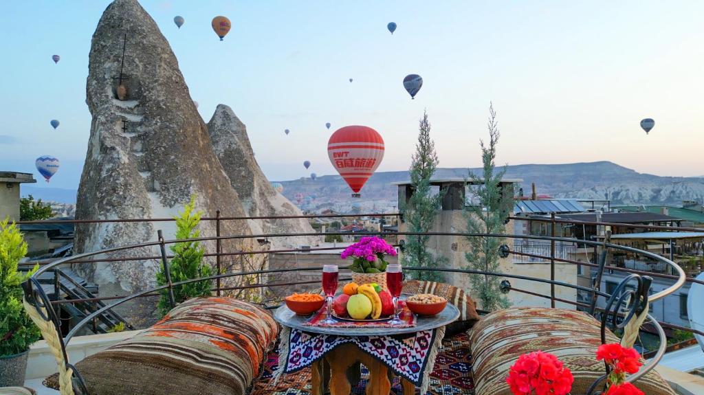 a table with fruit on a balcony with hot air balloons at Safran Cave Hotel in Göreme