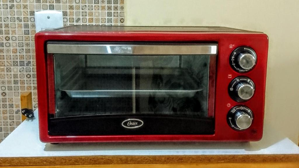 a red microwave sitting on top of a counter at Flores do Riacho- Chalés in São Miguel dos Milagres