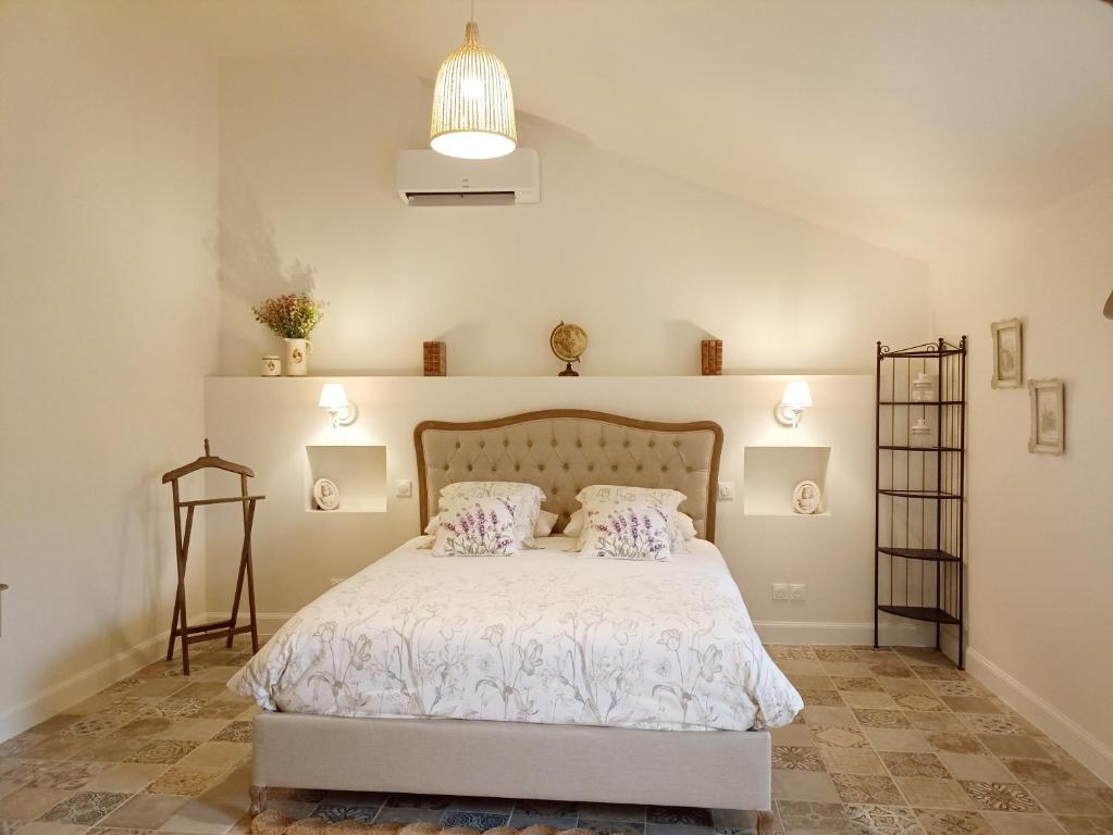 1 dormitorio con 1 cama blanca y 2 almohadas en Chambre d'hôtes Au Petit Bonheur, en Lorigné
