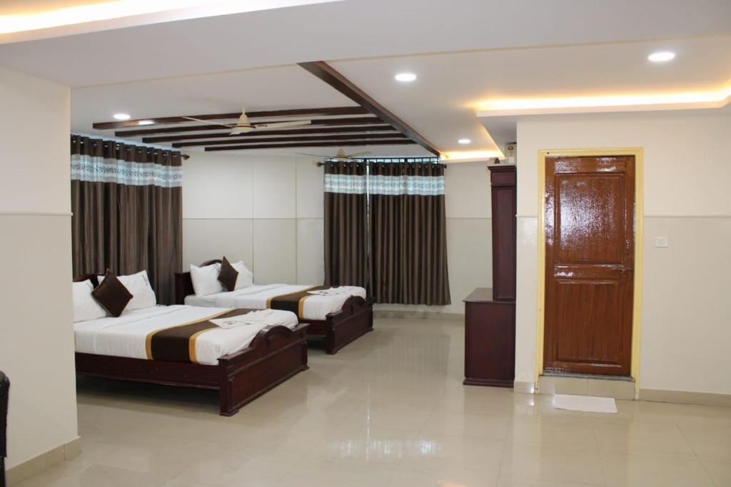 a hotel room with two beds and a television at MALDIVES INN in Bengaluru