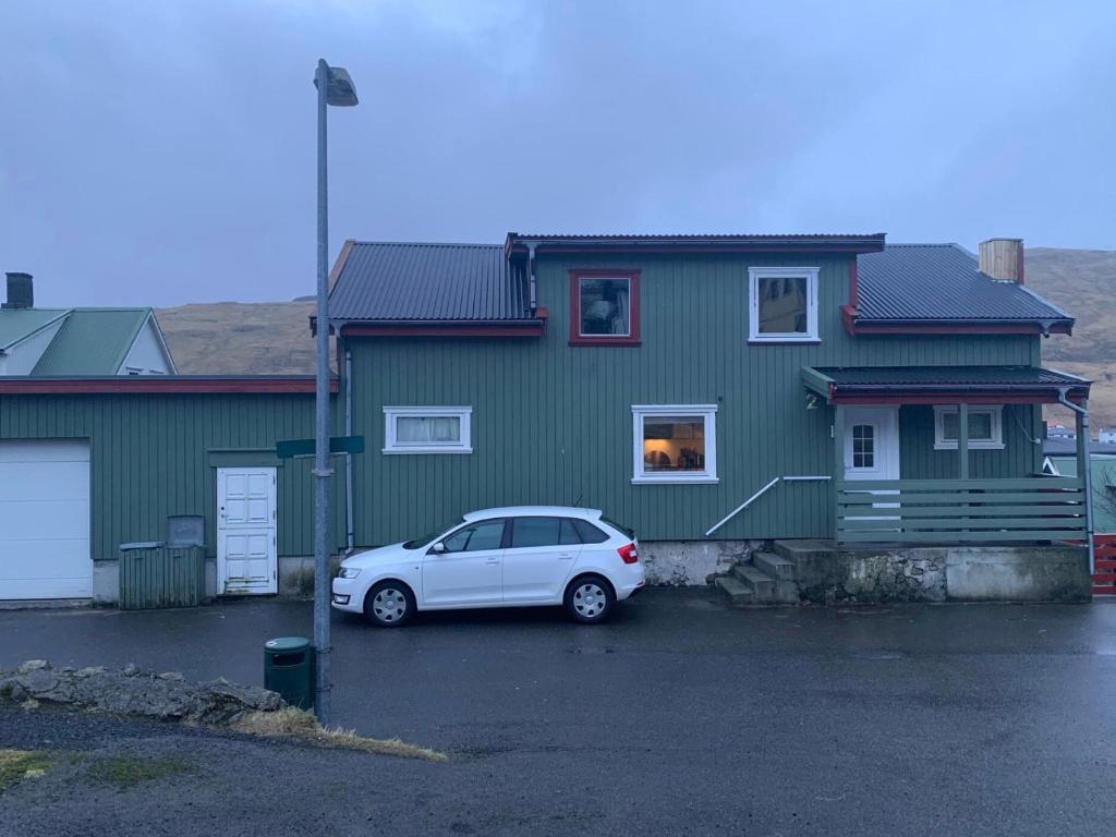 a white car parked in front of a green house at Peter’s guesthouse in Sandavágur
