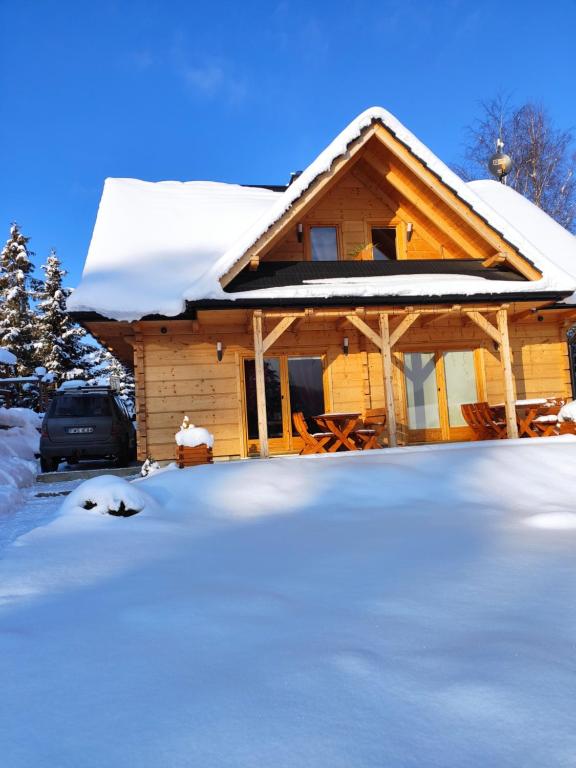 a house covered in snow with a car parked in front at Domek w Borowikowym Zaciszu in Falsztyn