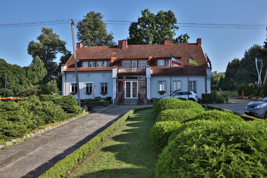 a white house with a red roof at Ašmonienės svečių namai "Senoji mokyklėlė" in Smalininkai