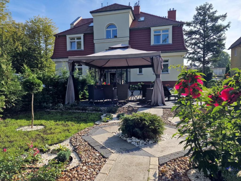 ein Haus mit einer Terrasse mit einem Sonnenschirm in der Unterkunft Villa Babette - Ubernachtung, Parkplatz, Kurtaxe, Wifi, Aufraumung - Alles im Preis! in Świnoujście