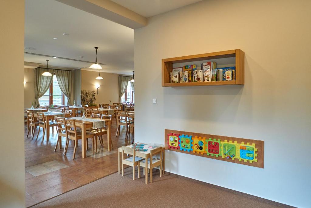 a dining room with tables and chairs and a book shelf at Hotel Toč in Lipova Lazne