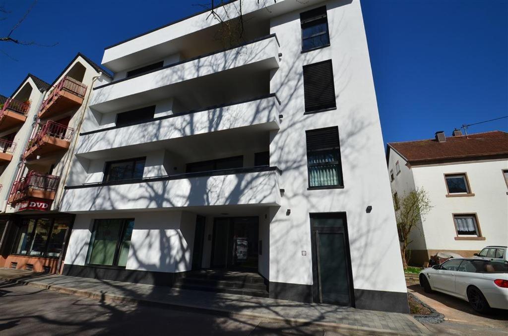 a white building with a car parked in front of it at EG Ferienwohnung Merzig Stadt 60 qm PKW Stellplatz im Innenhof in Merzig