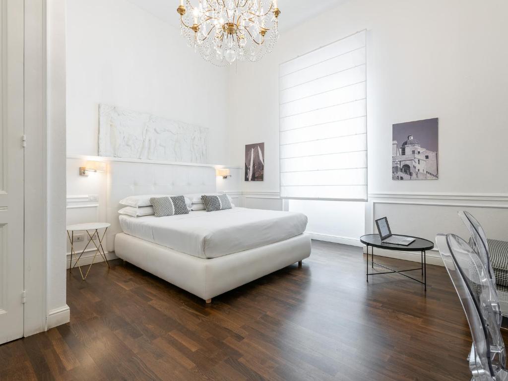 ein weißes Schlafzimmer mit einem Bett und einem Kronleuchter in der Unterkunft PLEY Cagliari Boutique Rooms in Cagliari