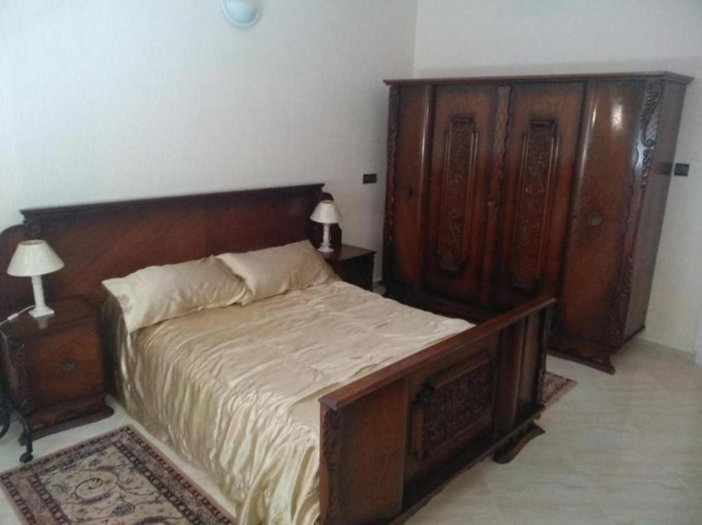 um quarto com uma cama e uma cabeceira em madeira em Appartement Bio Hamria Meknes em Meknès