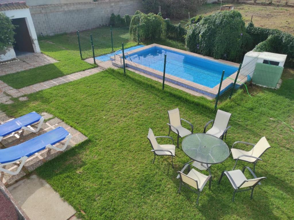 un cortile con tavolo, sedie e piscina di Casa Rural con Piscina Verdugo a El Puerto de Santa María