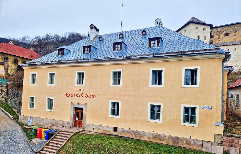 a large yellow building with a blue roof at Hostel Skautský dom in Banská Štiavnica