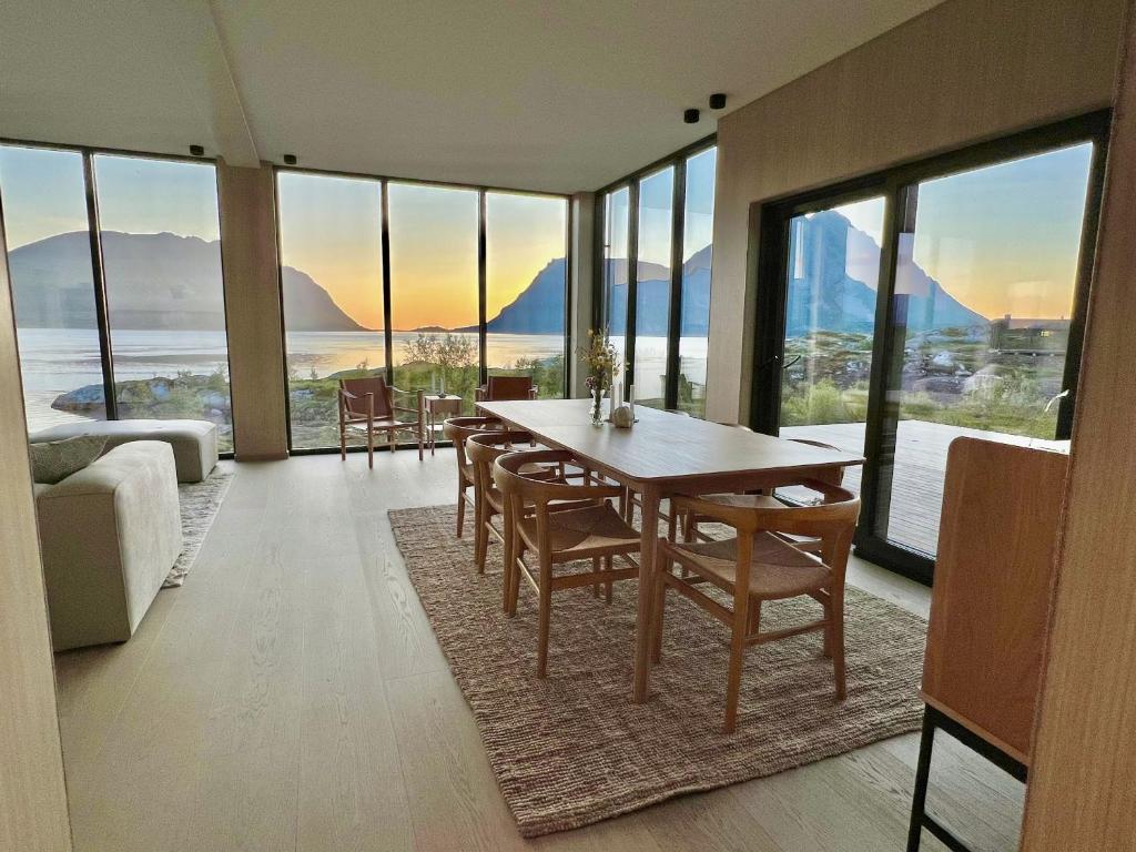 ein Esszimmer mit einem Tisch, Stühlen und Fenstern in der Unterkunft Luksushytte sentralt i Lofoten in Kleppstad